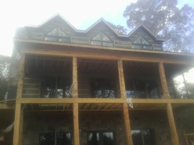 Dormers and porch framing on a large log home under construction — Roof Coating work by our crew in Chapman Ranch