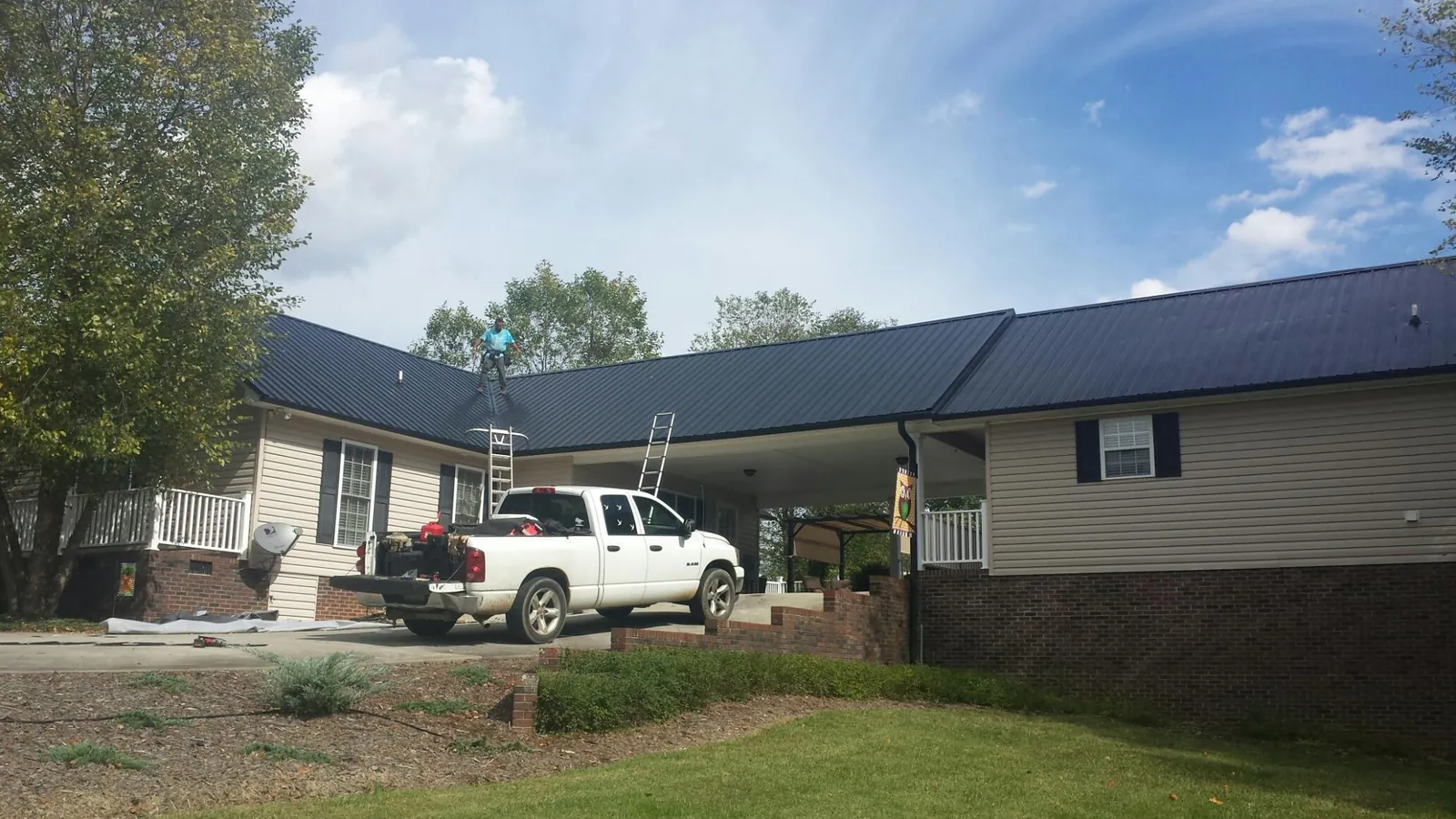 Black metal roof over a home and attached breezeway with ladders set in Chapman Ranch