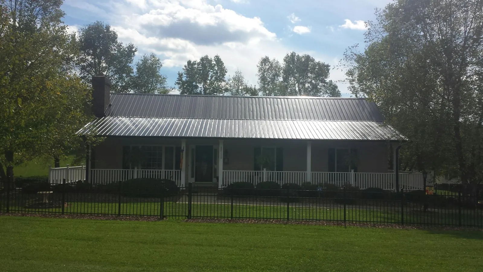 Gray metal roof on a brick ranch with a full width front porch — Gutter Guard Installation work by our crew in Chapman Ranch